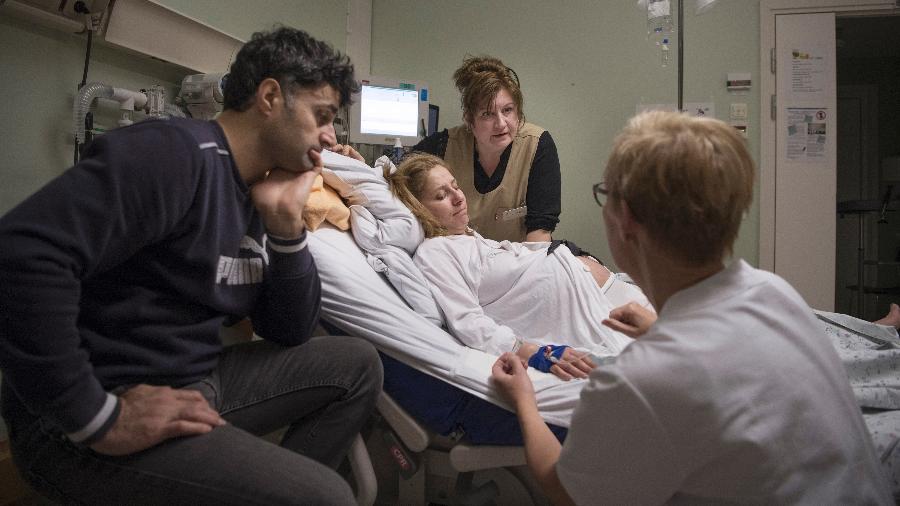 A doula Oksana Kornieko, centro, explica para a grávida Maria Hussein que a parteira Elisabeth Oskarsson sugeriu uma epidural, em Halmstad, a Suécia - Elisabeth Ubbe/The New York Times