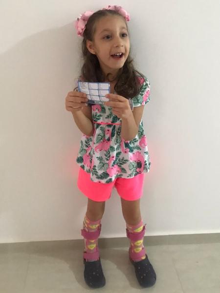 Catarina sorri com o cartão de vacinação contra a covid - Arquivo pessoal