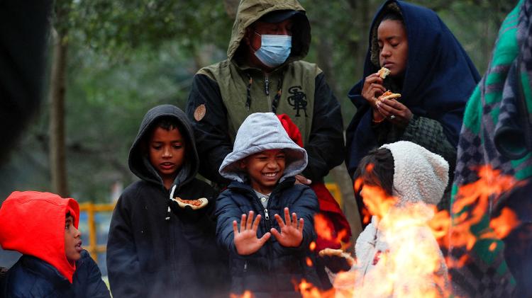 23.dez.22 - Imigrantes em busca de asilo se reúnem em torno de uma fogueira para se aquecer durante um dia de ventos fortes e baixas temperaturas em um acampamento improvisado perto da fronteira entre os EUA e o México