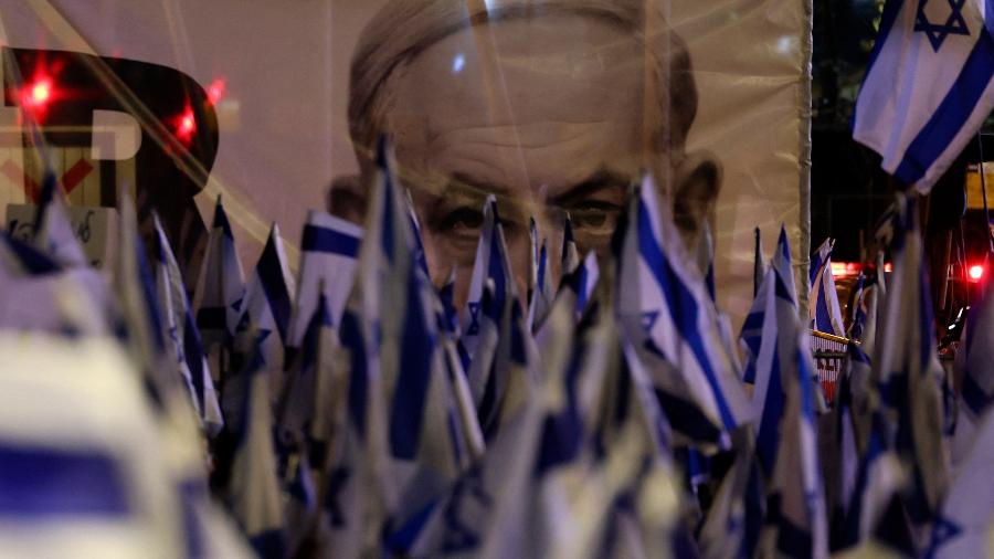 "Democracia! Democracia!" ou "Não vamos desistir!", gritavam os manifestantes no centro de Tel Aviv, em meio a um mar de bandeiras israelenses, na noite deste sábado (25) - JACK GUEZ/AFP