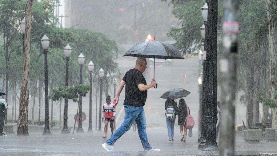 Pedestres enfrentam chuva forte na região central da cidade de São Paulo na tarde de domingo