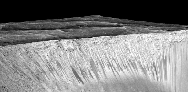 Em imagem divulgada pela Nasa é possível ver as listras estreitas e escuras onde os cientistas acreditam que exista água em estado líquido fluindo no solo de Marte - Universidade do Arizona/ NASA/JPL