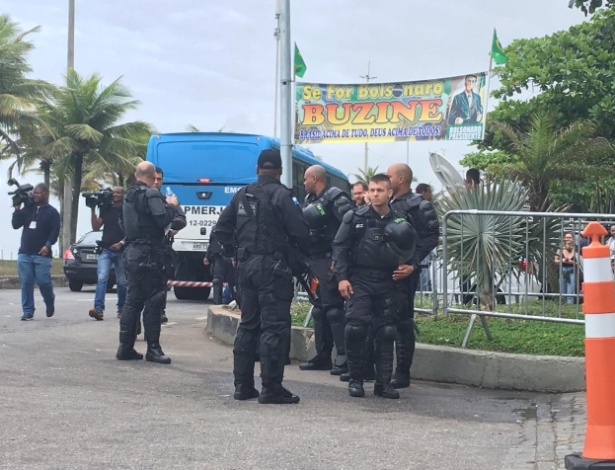 Policiais militares numerados e com equipamentos de proteção antidistúrbio (que costumam atuar em manifestações e grandes eventos) estão posicionados em frente ao condomínio de Bolsonaro