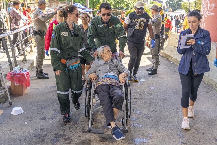 Idosa recebe a ajuda de voluntários em Porto Alegre nesta quinta-feira (9)