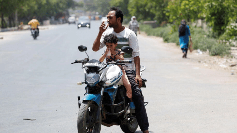Um homem e uma criança bebem refrescos oferecidos por moradores locais durante uma onda de calor em Nova Delhi, na Índia, nesta quarta-feira (29)  