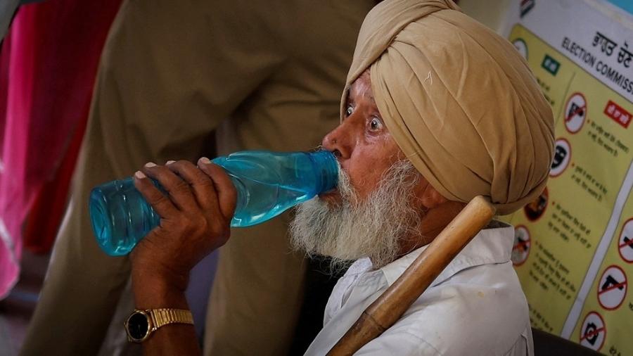 Agente de votação bebe água durante última fase das eleições na Índia