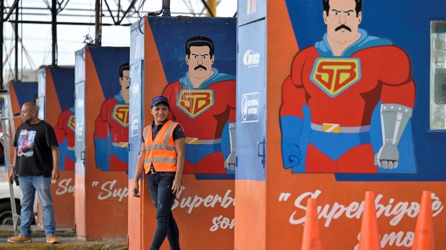 Um trabalhador está nos pedágios do estado de Naguanagua-Valência, na Venezuela, em 30 de junho de 2024, exibindo caricaturas do presidente da Venezuela, Nicolás Maduro, como "Super Bigode"
