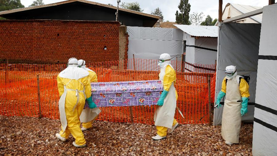 Profissionais de saúde usam equipamentos de proteção individual enquanto carregam o caixão de uma mulher congolesa morta por ebola - Baz Ratner/Reuters