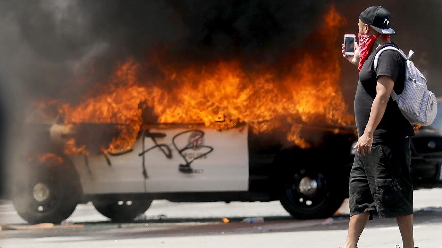Viatura incendiada em protesto contra brutalidade policial em Los Angeles - Maria Tama / AFP