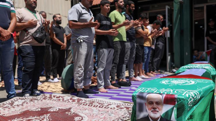 Manifestantes rezam perto de um caixão falso durante protesto contra o assassinato de Ismail Haniyeh. A morte de Haniyeh pode culminar em ataques de retaliação contra Israel