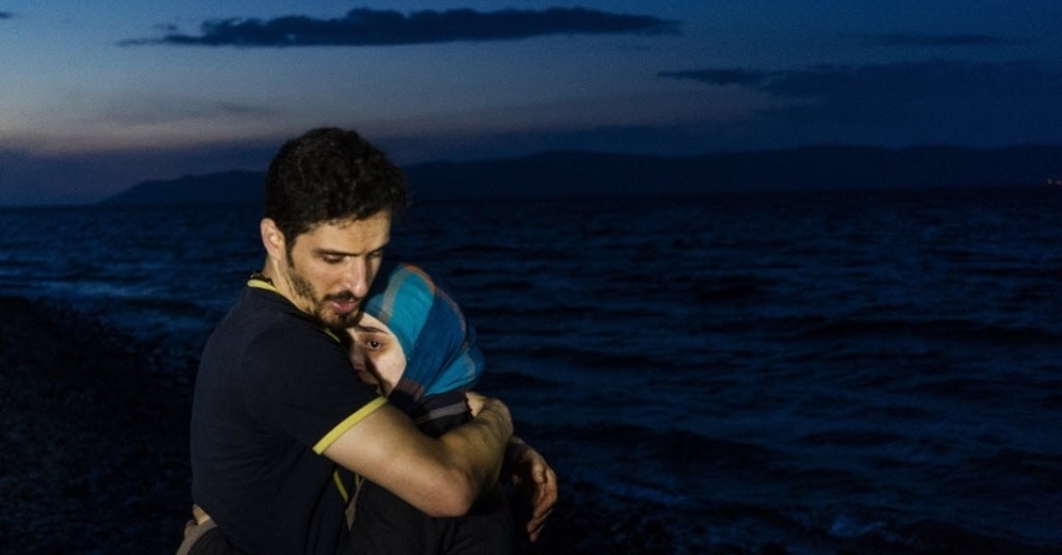 9.out.2015 - Um homem abraça sua mulher ao chegar com outros migrantes em um barco na ilha de Lesbos, na Grécia, após atravessar o mar Egeu saindo da Turquia