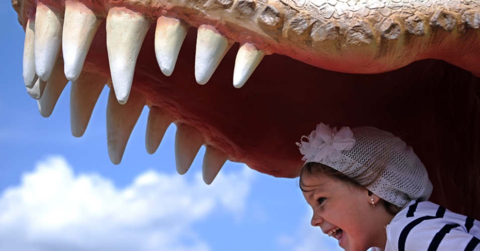 31.jul.2015 - Garota posa para foto dentro da boca de um boneco de dinossauro, na abertura do parque dos dinossauros, na cidade de Minsk (Belarus)