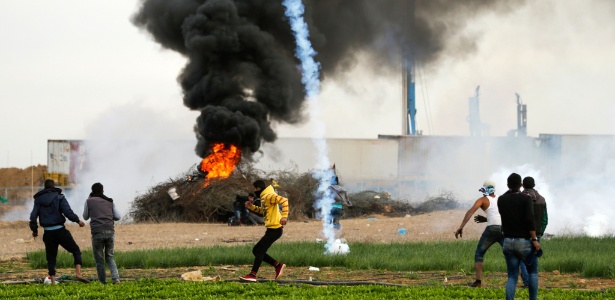 Uma caixa de gás lacrimogêneo cai perto de manifestantes palestinos durante conflitos com forças de Israel no sul da Faixa de Gaza - Mahmud Hams/AFP