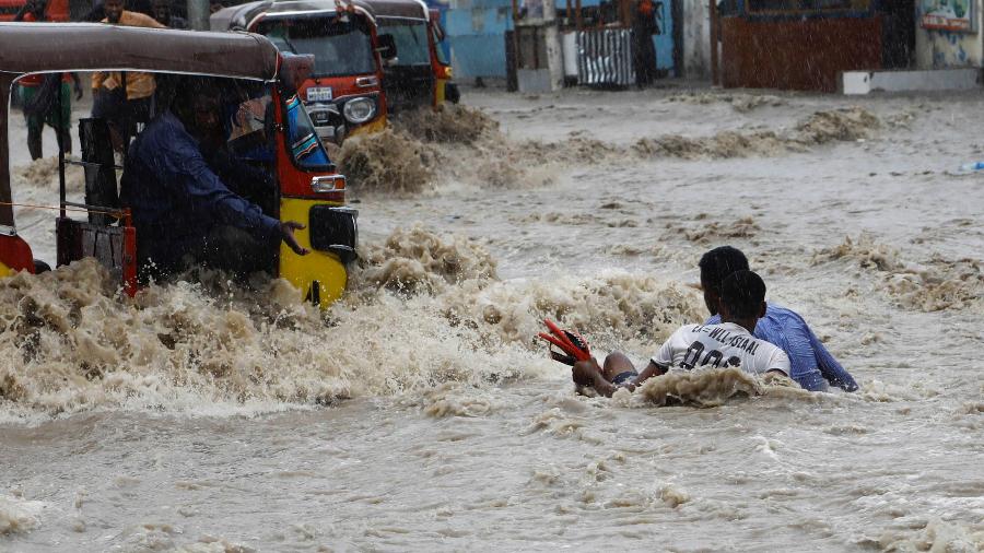 Um homem tenta resgatar um menino das fortes enchentes após fortes chuvas em Mogadíscio, Somália, 9 de novembro de 2023