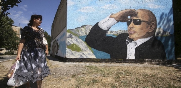 Moradora passa muro com grafite do presidente russo, Vladimir Putin, em Simferopol - Pavel Rebrov/Reuters