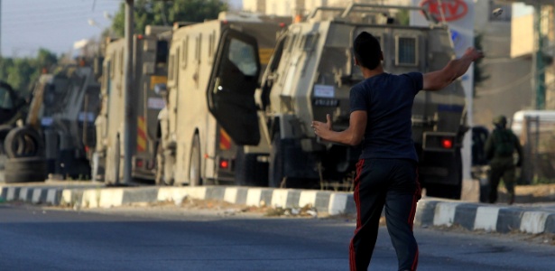 3.out.2015 - Manifestante palestino atira pedra contra soldados israelenses em rua de Nablus (Cisjordânia) - Jaafar Ashtiyeh/AFP