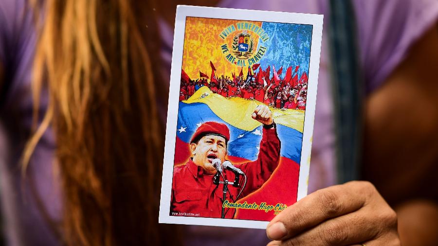 Apoiadora de Nicolás Maduro segura retrato de Hugo Chávez, ex-presidente do país morto em 2013 e uma das maiores lideranças venezuelanas - AFP