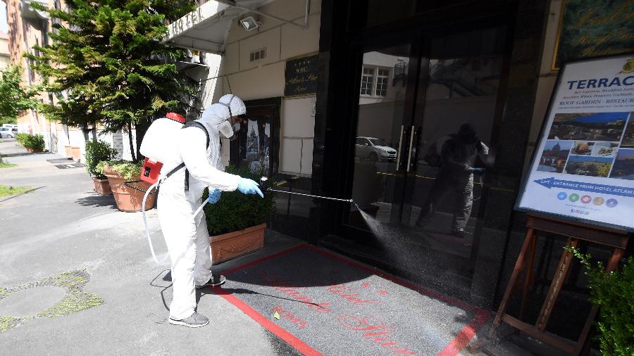 Um limpador usando um equipamento de proteção higieniza a entrada do Hotel Atlante Star Roma, perto do Vaticano, enquanto a Itália se prepara para um alívio gradual das restrições de bloqueio que foram impostas para combater a propagação do coronavírus - Alberto Lingria/Reuters