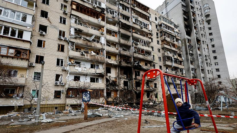 25.fev.2022 - Uma criança se senta em um balanço em frente a um prédio residencial danificado, depois que a Rússia lançou uma operação militar contra a Ucrânia, em Kiev - Umit Bektas/Reuters
