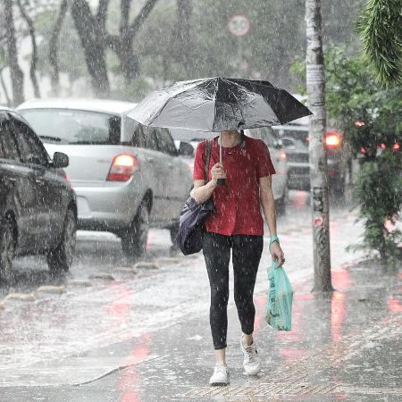 Pedestres se protegem de chuva no centro de São Paulo, na tarde deste sábado (2)