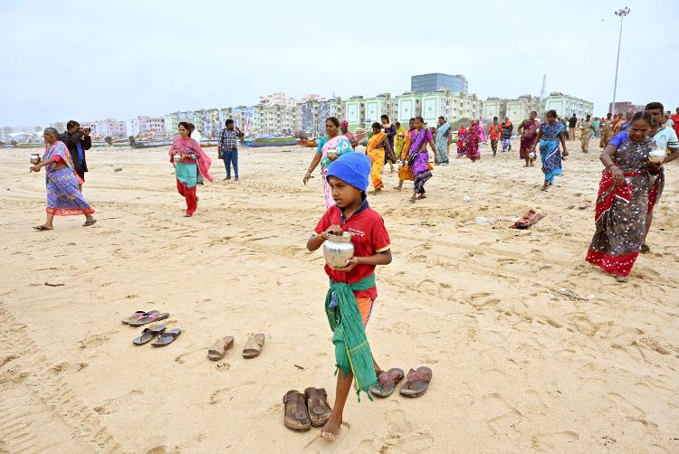 Pessoas carregam potes de leite para despejar na Baía de Bengala em um gesto de respeito às vítimas do tsunami do Oceano Índico de 2004, no 20º aniversário do desastre, na praia de Pattinapakkam, em Chennai, Índia, em 26 de dezembro de 2024 