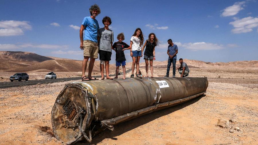 Pessoas em cima dos restos de um míssil iraniano no deserto de Neguev, perto de Arad, em Israel, após um ataque de míssil iraniano contra Israel