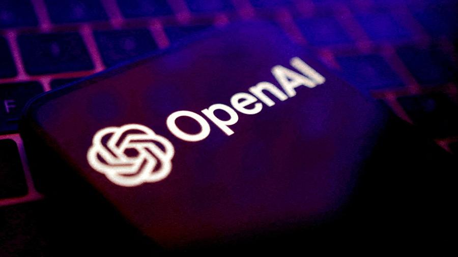 Logotipo da OpenAI, criadora do ChatGPT, em tela de celular com teclado ao fundo