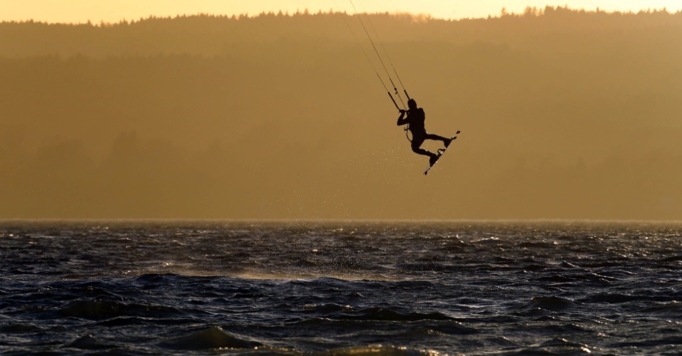16.nov.2015 - Praticante de kitesurf salta sobre a água durante o pôr do sol por trás do lago Ammersee, na Alemanha