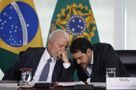Lula conversa ao pé do ouvido com o advogado-geral da União, Jorge Messias, durante cerimônia no Palácio do Planalto