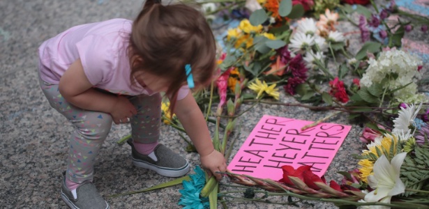 Criança coloca flores em memorial a Heather Heyer, jovem morta durante ato em Charlottesville, Virgínia - Scott Olson/Getty Images/AFP