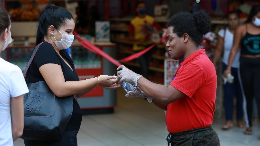  Funcionário de loja em Campinas (SP) aplica álcool gel nas mãos das pessoas em entrada de estabelecimento - Leandro Ferreira/Fotoarena/Estadão Conteúdo