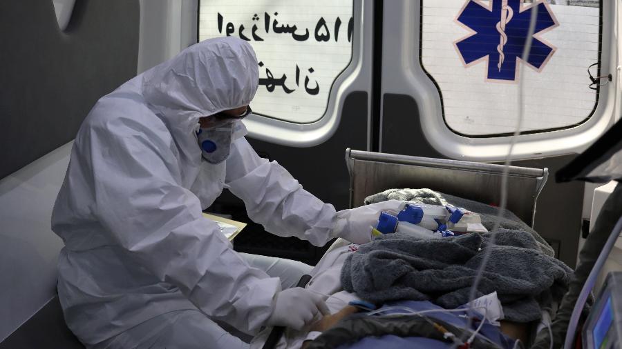 7.abr.2020 - Integrante de equipe médica aguarda transferência de paciente em ambulância no Irã - WANA NEWS AGENCY