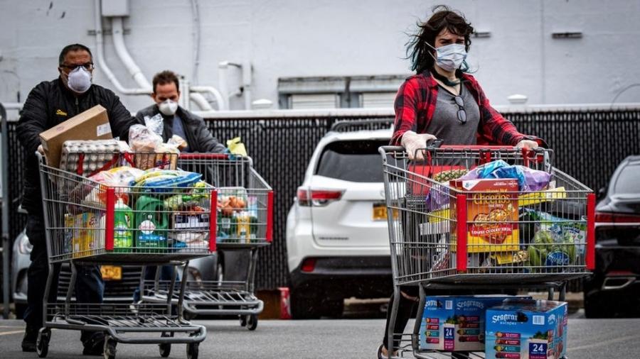 Consumidores americanos fora de um mercado com carrinhos cheios de compras - Getty Images