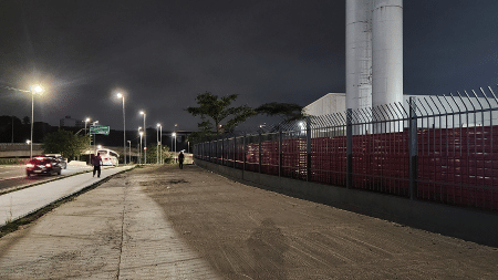 Calçada fica em frente a uma grade com chapas de aço, pertencentes a um galpão Calçada fica em frente a uma grade com chapas de aço, pertencentes a um galpão