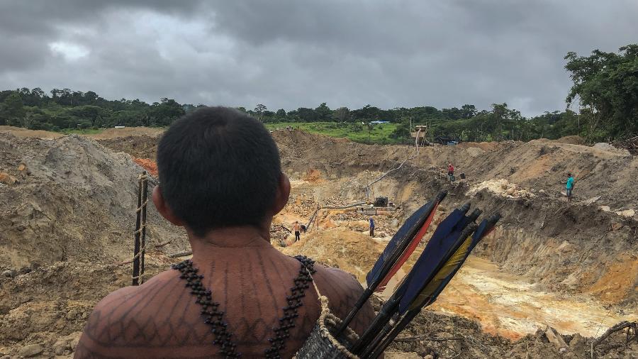 Guerreiro observa buraco aberto pelo garimpo ilegal na Terra Indígena Munduruku, sudoeste do Pará - Fabiano Maisonnave/Folhapress