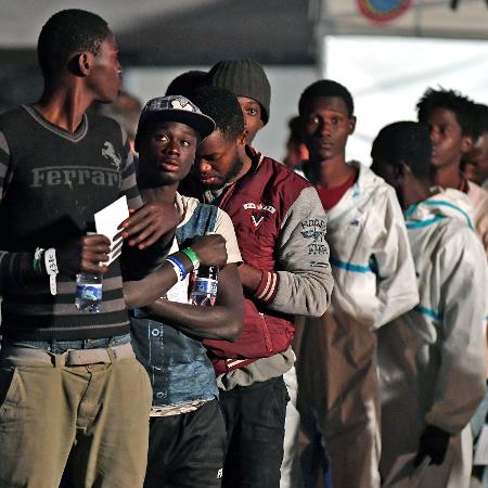 Africanos deixam embarcação na Itália após operação de resgate de imigrantes no mar Mediterrâneo - AFP PHOTO / Giovanni ISOLINO