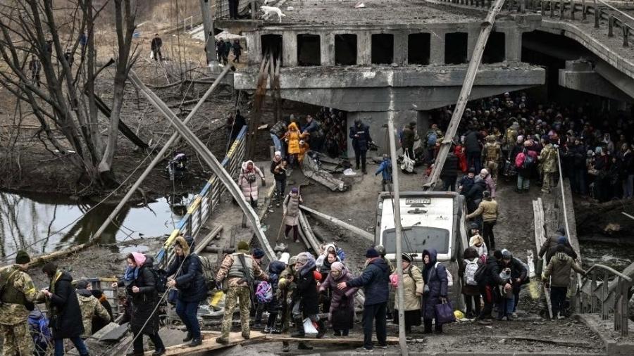 Pessoas atravessam uma ponte destruída durante evacuação da cidade de Irpin, no dia 5 de março de 2022 - Getty Images