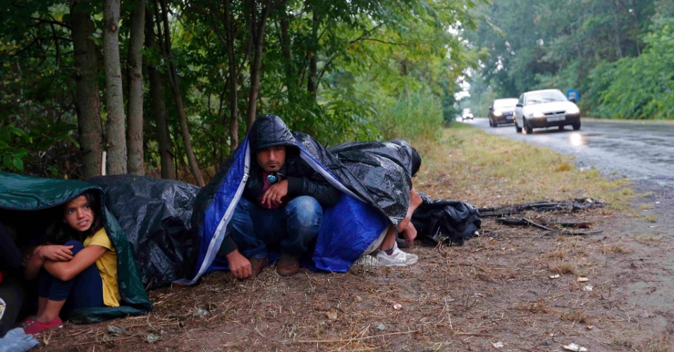 27.jul.2015 - Imigrantes usam sacos de dormir para se proteger da chuva enquanto descansam após cruzar ilegalmente a fronteira da Sérvia, próximo a Asotthalom, na Hungria