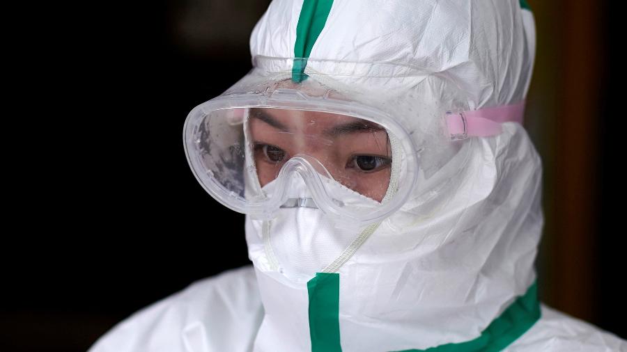 Agente de saúde com roupa de proteção aguarda resultado de exames para Covid-19 em Wuhan, epicentro da doença na China - ALY SONG