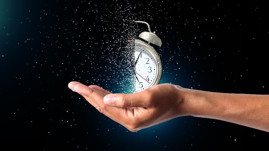 Relógio despertador se dissolvendo na mão de uma pessoa; pressa; falta de tempo; ansiedade - Indu Bachkheti/iStock