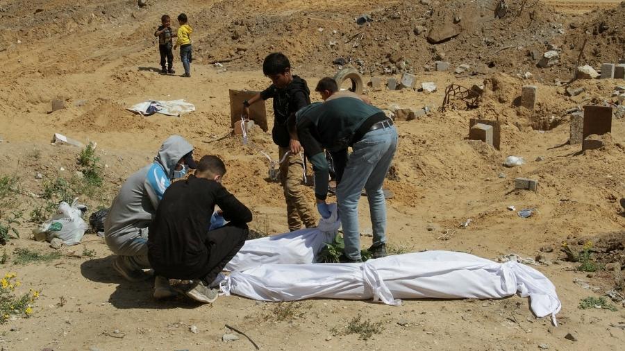Palestinos cobrem corpo encontrado em vala comum na Faixa de Gaza -  REUTERS/Mahmoud Issa