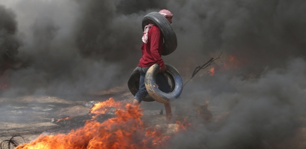 20.abril.2018 - Homem carrega pneus durante protestos de palestinos na faixa de Gaza  - Ibraheem Abu/Reuters