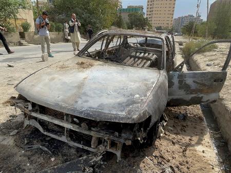 30.ago.2021 - Homens afegãos tiram fotos de um veículo do qual foguetes foram disparados, em Cabul, Afeganistão - Stringer/Reuters