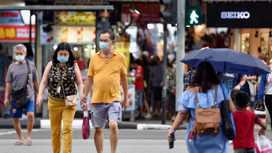 03.nov.2021 - Pessoas com máscaras de proteção contra a covid-19 atravessam uma rua, em meio à pandemia do novo coronavírus, em Singapura. - REUTERS/Caroline Chia
