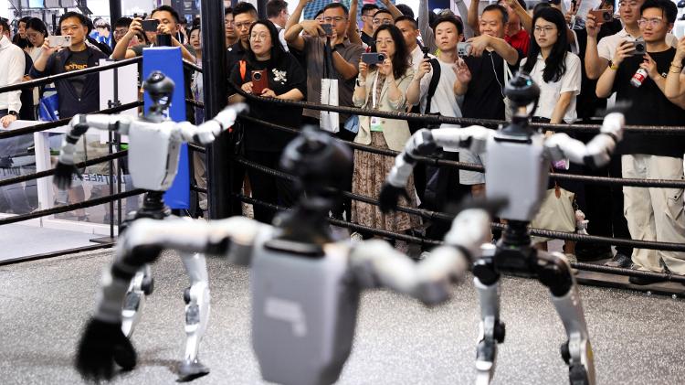  17.jul.2026 - Pessoas observam robôs humanoides da Unitree Robotics em estande de evento em Xangai, na China