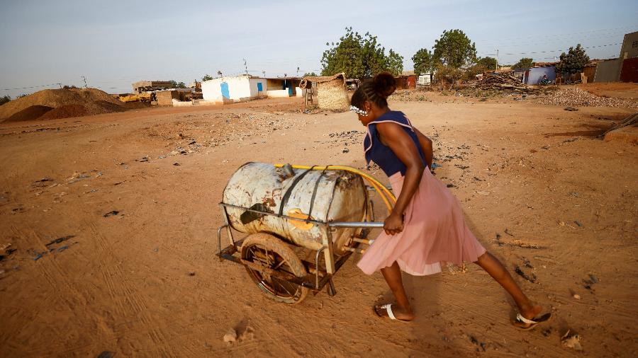 Mulher empurra carregamento de água em Ouagadougou, capital de Burkina Faso - ZOHRA BENSEMRA/REUTERS