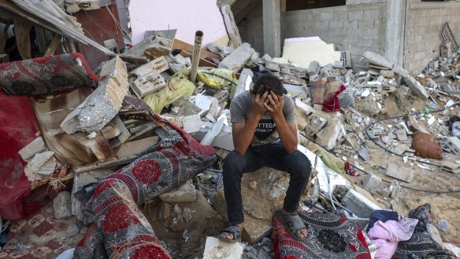 Palestino em meio aos escombros após ataque de Israel a campo de refugiados em Rafah, no sul da Faixa de Gaza