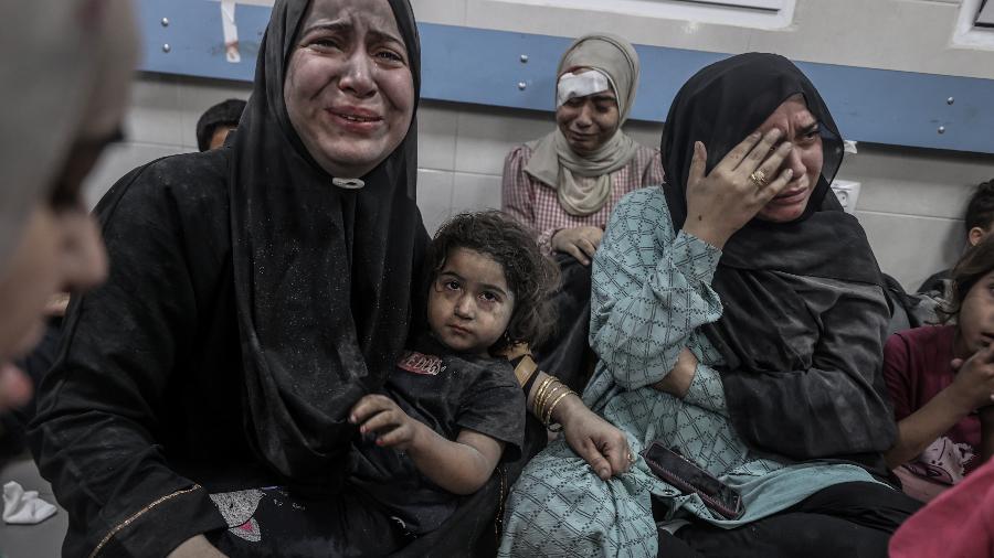 Palestinos feridos no ataque ao hospital Al-Ahl, em Gaza, esperam atendimento no hospital Al-Shifa, para o qual foram levados