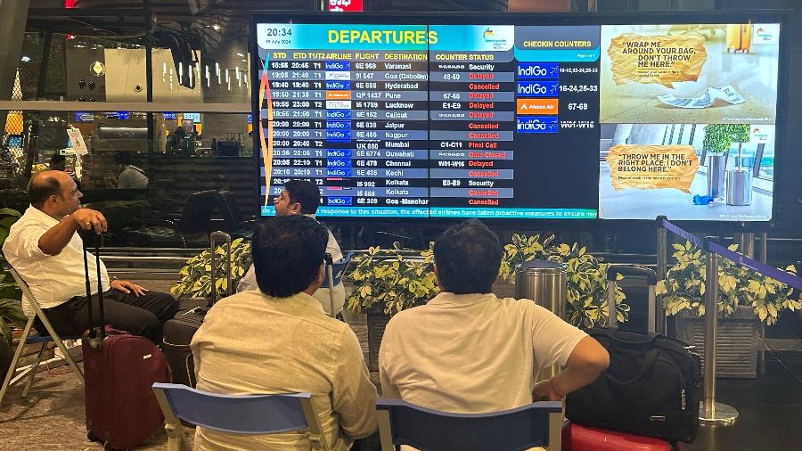 19.jul.2024 - Passageiros olham para um painel de informações no Aeroporto Internacional de Kempegowda após o apagão - REUTERS/Nandan Mandayam