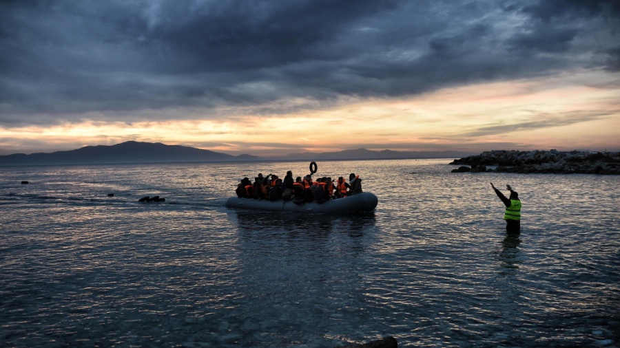 17.fev.2016 - Membro de equipe de resgate acena para bote inflável lotado de imigrantes no norte da ilha de Lesbos, na Grécia, após a embarcação cruzar o mar Egeu, saídos da Turquia - Aris Messinis/AFP